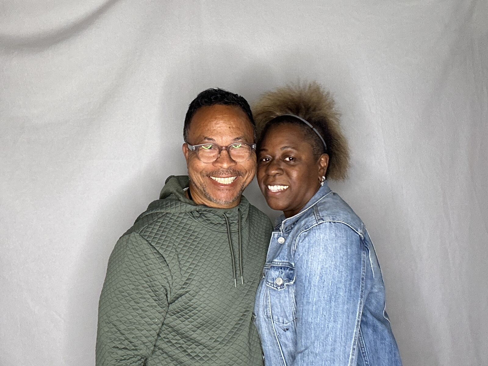 Two guests smiling cheek to cheek in a photo taken by the booth in front of a grey backdrop