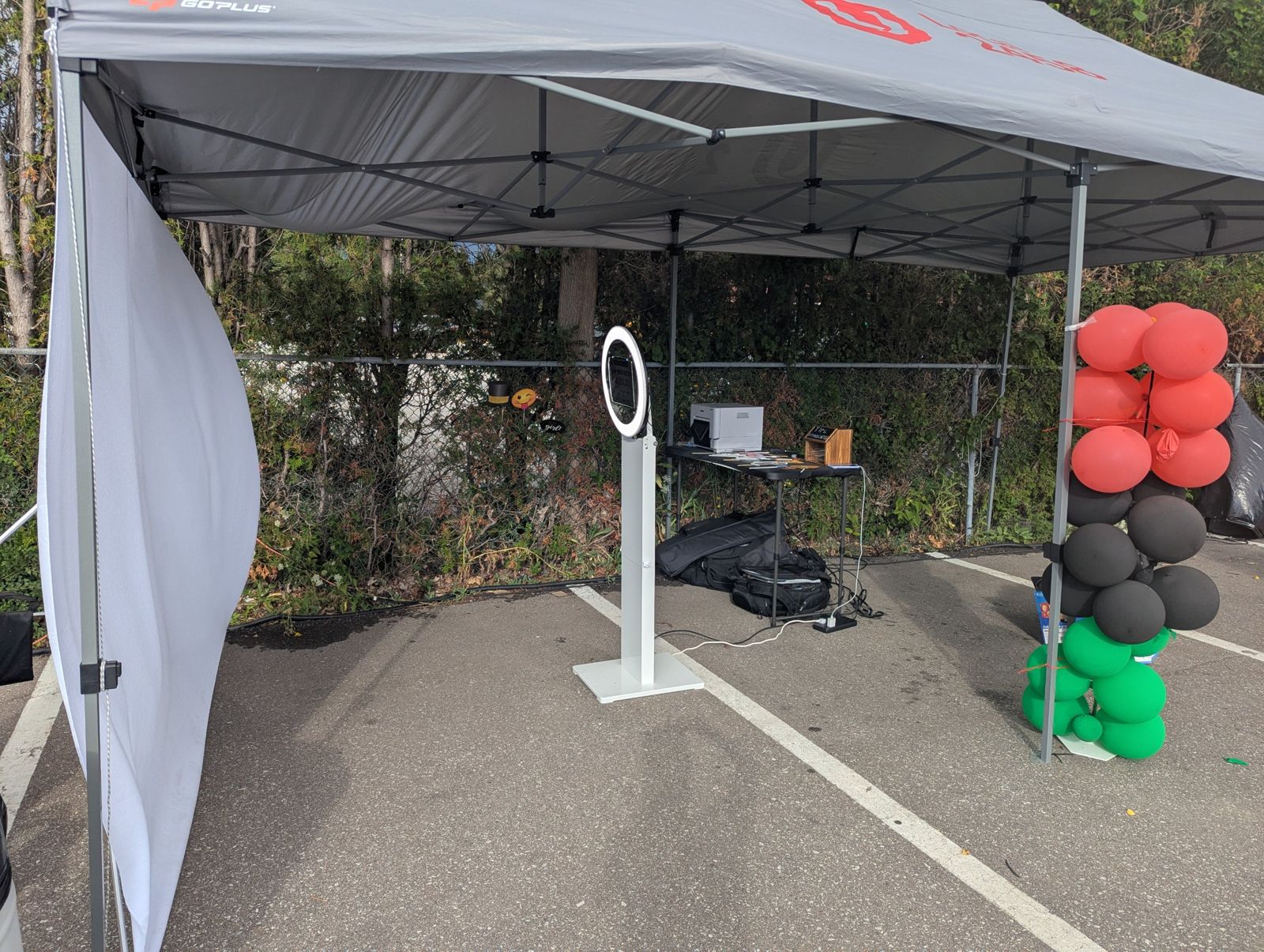 The booth set up outdoors under a tent with a backdrop, printer and props table